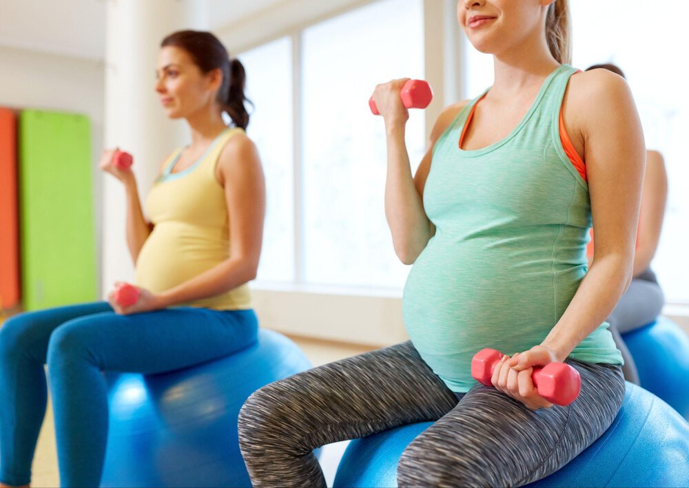 Ciężarne kobiety w kolorowych strojach sportowych wykonują ćwiczenia na piłkach.